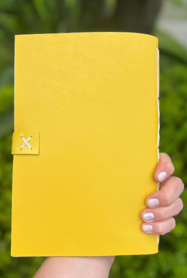 Verso de caderno amarelo com pequeno detalhe azul na capa